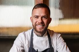 smilig white man with short brown hair in chef white jacket