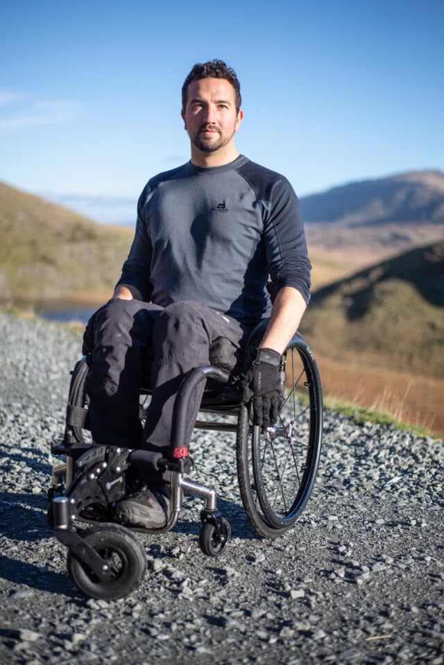 man in wheelchair wearing grey sports top & trousers