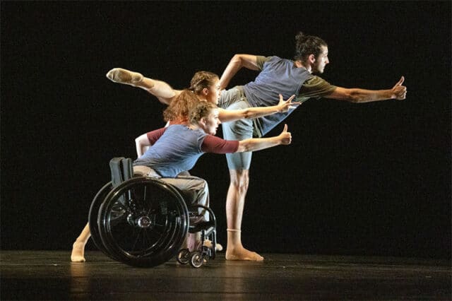 3 people one in a wheelchair stretching forward on a blc background