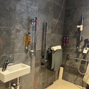 shower with grey tiles and shower seat plus red cords tied up